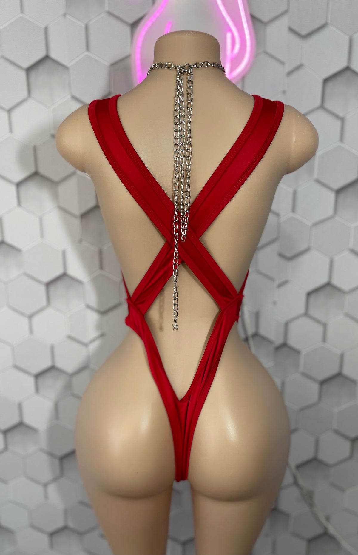 Red thong bodysuit back view showing X-cross strap design with dangling chain detail
